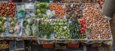 Portekiz, Funchal 'da parlak sonbahar ışığı altında çekilen kapalı pazar tezgahında renkli sebzeler yığını ile yukarıdan bakıldığında,