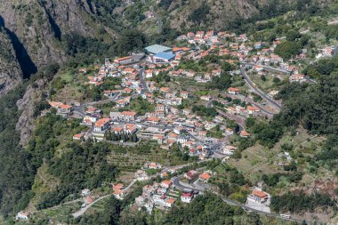 Madeira adasının yeşil iç kısımlarındaki Curral des Freiras adlı dağ köyü ile hava manzarası, Portekiz 'in Miradouro Eira do Serrado kentinden parlak sonbahar ışığı altında çekilmiştir.