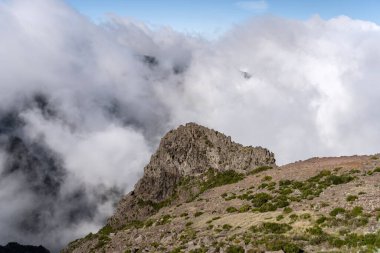 Areeiro 'nun kuzeyindeki bulutlardan yükselen volkanik kayalıklı manzara, zirveden parlak bir sonbahar ışığı altında çekildi, Madeira, Portekiz