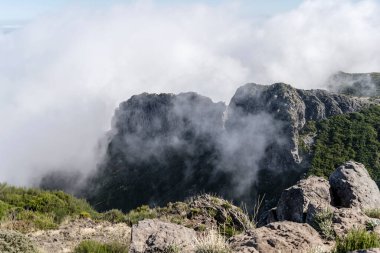 Miradouro de Areeiro zirvesinin doğusundaki Madeira adasının iç kısımlarındaki volkanik sarp kayalıkları yutan bulutlu manzara, Portekiz 'in parlak sonbahar ışığı altında çekildi.