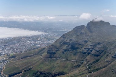 Table Dağı 'nın doğu yamaçlarındaki dolambaçlı yolda alçak bulutlar arka planda, Cape Town, Batı Cape, Güney Afrika' da parlak yaz ışığında çekilen manzara.