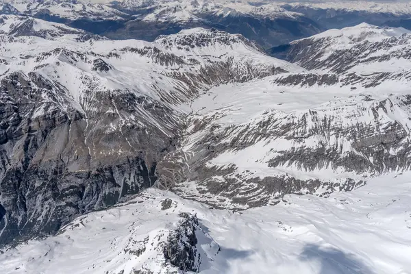 비행기를 타고스 고개를 바위투성이의 눈덮인 산비탈을 지나는 이탈리아 빛으로 서쪽에서 — 스톡 사진