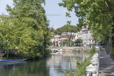 Sile nehri üzerindeki San Martino köprüsü ve Treviso, Veneto, İtalya 'da parlak ışıkta çekilen yeşil setlerle şehir manzarası