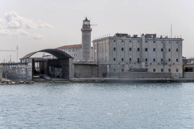 Teresiano rıhtımında Lanterna deniz feneri olan şehir manzarası, denizden bakıldığında parlak bir ışık altında çekilen, Friuli, İtalya
