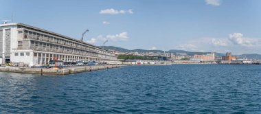 TRIESTE, ITALY - 29 Mayıs 2023: Limandaki binalar ve rıhtımda kuyruk oluşturmuş sayısız traktör ve koçla dolu şehir manzarası, 29 Mayıs 2023 'te Trieste, Friuli, İtalya