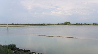  Tuzlu su bataklığı ve kanallı manzara göldeki levhalarla sınırlandırılmış, Grado, Gorizia, Friuli, İtalya 'da parlak ışıkta çekilmiş.