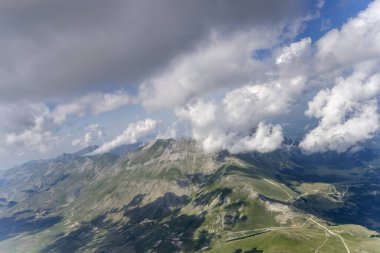 Vettore Tepesi 'nin çorak yamaçlarında, deniz meltemi bulutlarıyla çevrili, Arquata del Tronto, Apennines, Ascoli, Marche, İtalya yakınlarındaki parlak yaz ışığında güneybatıdan çekilen hava manzarası.