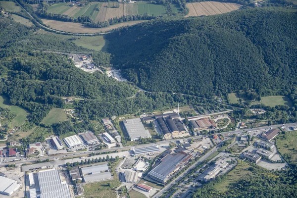 Rieti 'nin doğu semtlerindeki Salaria yolundaki endüstriyel binaların bulunduğu planörlü bir uçaktan çekilen hava manzarası. Parlak yaz ışığında kuzeydoğudan çekilen Apennines, Lazio, İtalya