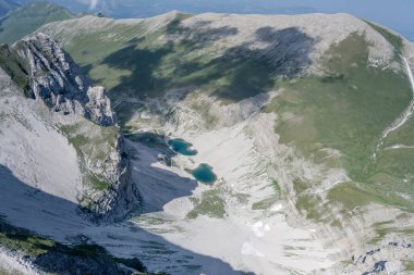 Pilato dağ gölü, güneybatıdan Arquata del Tronto, Apennines, Ascoli, Marche, İtalya yakınlarındaki parlak yaz ışığında çekilen Vettore tepelerinin ve çorak yamaçların arasındaydı.