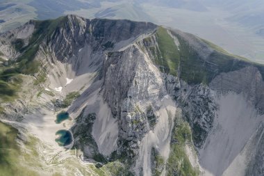 Pilato dağ gölü, kuzeydoğudan Arquata del Tronto, Apennines, Ascoli, Marche, İtalya yakınlarındaki parlak yaz ışığında çekilen Vettore tepelerinin ve verimsiz yamaçların arasındaydı.