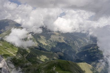 Kuzeyden Norcia, Apennines, Perugia, Umbria, İtalya yakınlarındaki parlak yaz ışığında çekilen Vettore sıradağlarının ve deniz meltemi bulutlarının çorak doğu yamaçlarından oluşan bir planör uçağının havası.