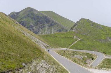 Leonessa eyerinden, Apeninlerden, Rieti 'den, Lazio' dan, İtalya 'dan parlak yaz ışığında çekilen, Terminillo sıradağlarının köşesinde, tanınmayan bir motosikletlinin olduğu manzara.