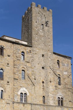 Volterra, Toskana, İtalya 'da sonbaharın ilk ışıklarıyla Priori Meydanı' ndaki kule ve taş cepheli şehir manzarası.