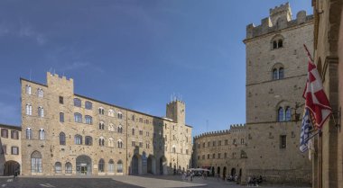 VOLTERRA, 2023 Eylül; 30 Eylül 2023 'te Volterra, Toskana, İtalya' da parlak bir sonbahar ışığı altında Priori Meydanı 'nda güneşli bir günün tadını çıkaran turistlerle şehir manzarası