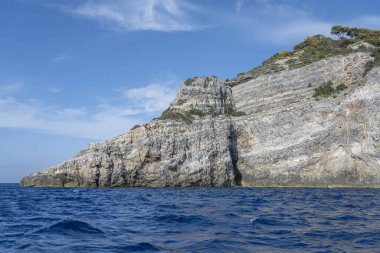 Piatti Burnu 'nun dik katmanlı kayalıklarıyla Akdeniz kıyısında, Argentario, Tuscany, İtalya' da parlak sonbahar ışığı altında bir tekneden çekilen manzara.