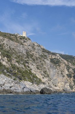 Uomo Burnu 'nda, Maddalena kıyısındaki kayalık kayalık kayalıkların olduğu, Argentario, Tuscany, İtalya' da sonbahar güneşinde parlak bir kayıktan çekilen eski kule enkazı.