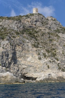 Maddalena 'nın dik kayalık kayalıkları üzerindeki eski kule harabeleri Akdeniz kıyısındaki promontory' de Arjantario, Tuscany, İtalya 'daki parlak sonbahar güneşinde bir tekneden çekilen manzara.
