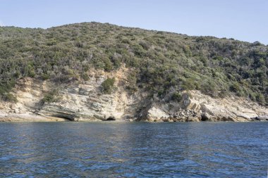 Torre Ciana Burnu 'ndaki küçük körfezli manzara, Arjantario, Toskana, İtalya' da sonbahar sabahının erken saatlerinde parlak bir tekneden çekildi.