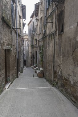 Pitigliano, Tuscany, İtalya 'da sonbaharın parlak erken saatlerinde çekilen, dağlık tarihi köyde, dar sokaktaki medikal evlerle şehir manzarası.