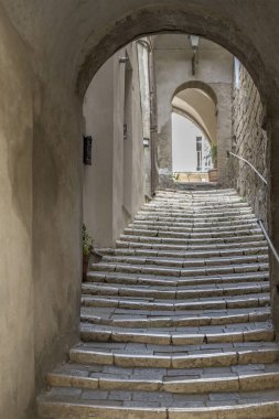 İtalya 'nın Tuscany, Pitigliano şehrinde sonbaharın parlak erken saatlerinde çekilen, tepenin zirvesindeki tarihi köyde merdivenlerin dar olduğu şehir manzarası.