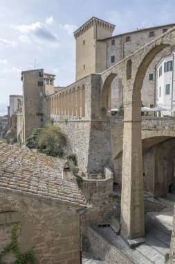 Medicean acqueduct arcade ve arka planda Orsini kale kulesi ile şehir manzarası tepe tarihi köyde, Pitigliano, Toskana, İtalya 'da parlak bir sonbahar ışığı altında çekildi