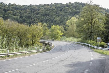 İtalya 'nın Tuscany, Pitigliano şehrinde parlak bir sonbahar ışığı altında çekilen, küçük Lente nehri üzerindeki bükülmüş bir köprü.