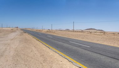 Çöl kırsalında katranlı yol manzarası, Usakos, Namibya, Afrika yakınlarındaki parlak bahar ışığı altında çekilmiş.
