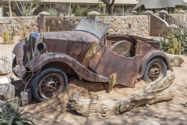 Naukluft Çölü 'ndeki benzin istasyonunda paslanarak yıpranmış eski bir araba enkazı Solitaire, Namibya, Afrika' da parlak bir bahar ışığı altında çekildi.