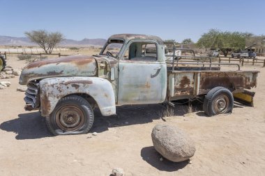 Naukluft Çölü 'ndeki benzin istasyonunda paslanarak yıpranmış eski bir kamyonet enkazı Solitaire, Namibia, Afrika' da parlak bir bahar ışığı altında vuruldu.