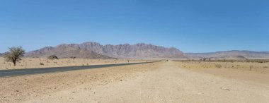 Zift yolu ve Naukluft Çölü 'ndeki Naukluftberge dağ sıraları Susriem, Namibya, Afrika yakınlarındaki parlak bahar ışığı altında çekilmiştir.