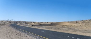 Sperrgebiet çölünde kum tepeleri ve B4 katran yolu olan manzara, Luderitz, Namibya, Afrika yakınlarındaki parlak bahar ışığı altında çekildi.