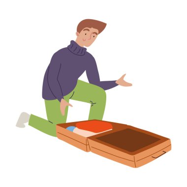 Genç adam açık bir bavul hazırlarken diz çöküyor.