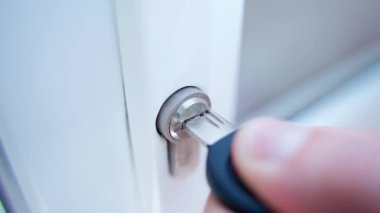Kilit için uygun bir anahtar seçimi yapın. Delinmiş bir anahtar, beyaz bir kapının anahtar deliğine yerleştirilir. Kapıyı açmak ya da kapatmak. Yüksek kalite 4k görüntü