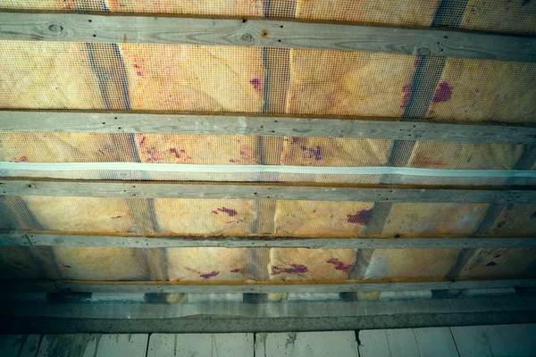 Insulated wooden floor between floors in a private house. Protection of sound and heat insulation with a vapor barrier and a hydro barrier. Wooden lathing of the ceiling under a layer of glass wool