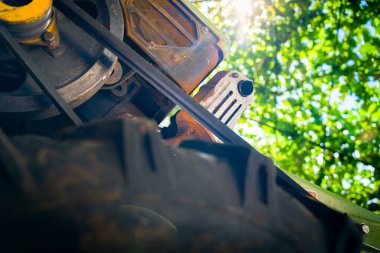 Tarım için eski bir motoblock, bulanık bir arka planda yeşil yaprakların arka planına karşı aşağıdan öngörülen görünüm