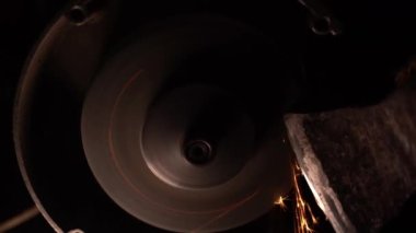 Balta, gece bir öğütücüde keskinleştirilir. Karanlıktaki bir dosyadan kıvılcımlar çıkıyor. Tarım araçlarının keskinleştirilmesi. Tehlikeli endüstriyel işler. Yüksek kaliteli FullHD görüntüler