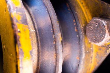 Köşelerinde aşınma olan V-makara, yakın plan. Eski, yıpranmış çift makara traktör. Tarım makinelerinin demir parçalarında pas var.