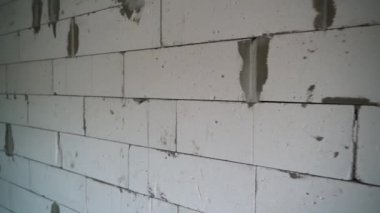 Kameranın havalanan beton bloklardan oluşan duvar boyunca düzgün bir hareketi var. İnşaat sırasında evin çıplak duvarları. Yüksek kaliteli FullHD görüntüler