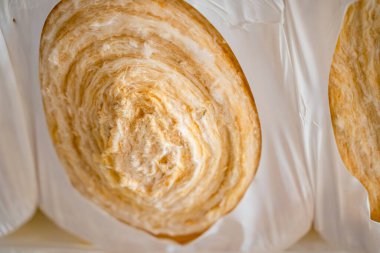 Bir rulo cam yünü yakın çekim. Küresel yalıtım ve yünden yapılmış ses yalıtımı. İnşaat alanında inşaat malzemeleri.