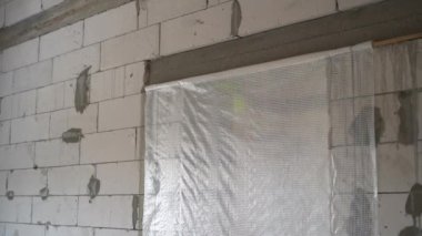 Kapı bir buhar bariyeriyle kapatılmış. Beyaz havalandırmalı beton tuğlalardan yapılmış tamamlanmamış bir evin çıplak duvarları. Pürüzsüz kamera hareketi. Yüksek kaliteli FullHD görüntüler