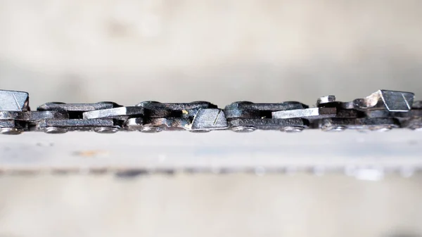 Close-up of a chainsaw chain on a tire on a blurred background, top view