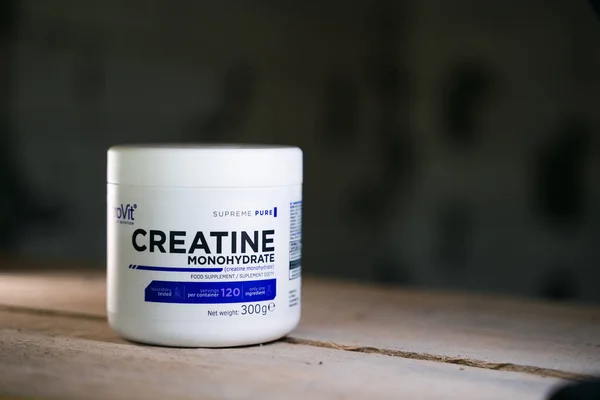 Kyiv, Ukrayna - 16 Ekim 2022: Bulanık bir arkaplanda Ostrovit firmasından toz şeklinde bir kreatin kavanozu. Tahtaya spor takviyesi.