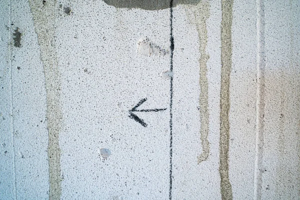 An arrow drawn with a pencil on a gas block wall close-up. The line drawn on the wall of aerated concrete bricks for builders. Clarification when repairing a private house. direction symbol