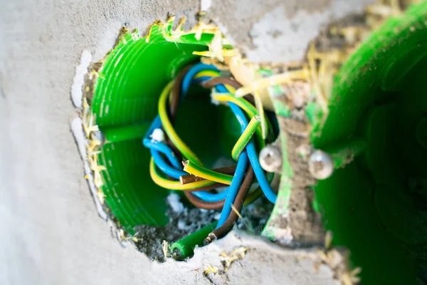 Multi-colored wires in a green socket under the socket on the facade of the house. Installed close-up mortgage for future electronics on the street in a private house