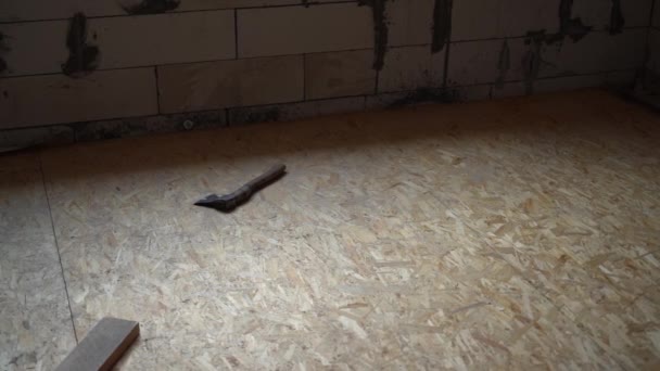 新築の民家のOsbラフフロア 斧は木製の床の上にある コンクリートレンガの壁を負担します 高品質のフルHd映像 — ストック動画