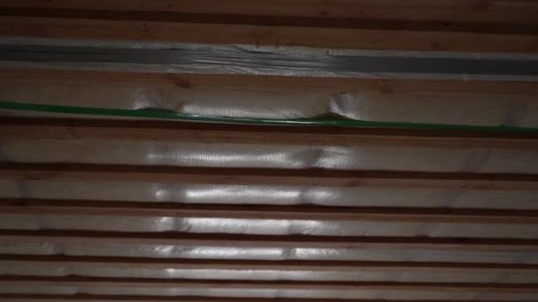 天井はガラスウールで断熱され 蒸気バリアで覆われ 木製のクレートが閉じ込められています 未完成の民家の断熱屋根に沿って滑らかなカメラの動き — ストック動画