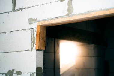 İnce havalandırmalı beton bloktan yapılmış bir duvardaki kapı aralığının yakın çekimi. Özel bir evde bitmemiş bir yenileme. Çıplak beton duvarlar