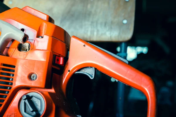 Orange chainsaw close-up. Gasoline tool controls, off button and gas pedal. Filler neck of the tank for the fuel mixture
