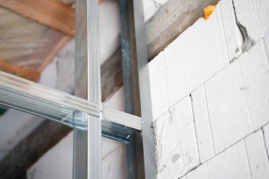 Fastening a frame from a metal profile to an aerated concrete wall. Interior partition design. Preparation for sheathing with gypsum board. Connection of a metal profile with self-tapping screws