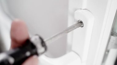 White plastic doors are screwed with a screwdriver close-up. The process of dismantling or breaking a door. Phillips screwdriver unscrews the handle fixing screw. High quality 4k footage